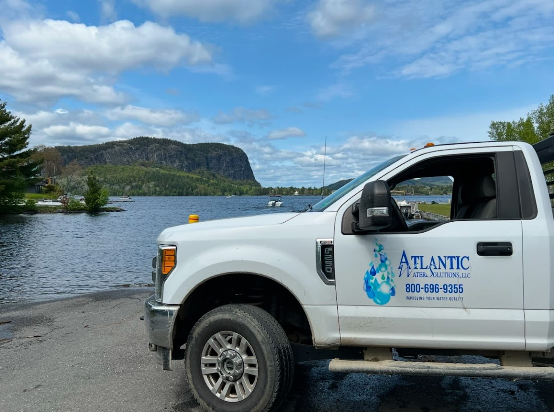 Atlantic Water service truck beside a lake with a mountain behind